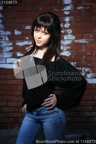 Image of fashion portrait of young woman with a brick wall