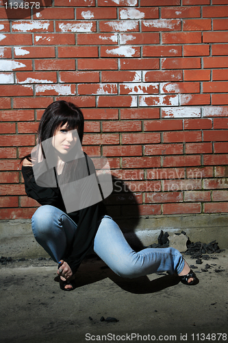 Image of fashion portrait of young woman with a brick wall