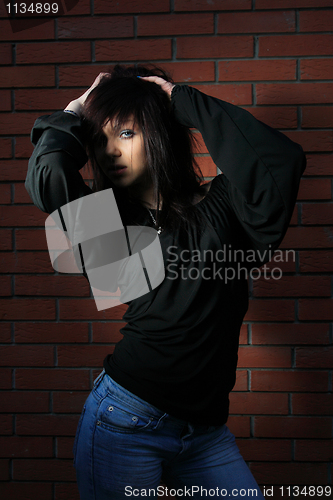 Image of fashion portrait of young woman with a brick wall