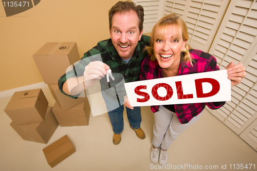 Image of Goofy Couple Holding Key and Sold Sign Surrounded by Boxes