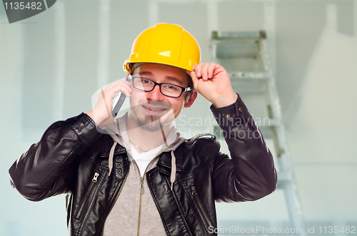 Image of Contractor in Hard Hat on Cell Phone In Unfinished House