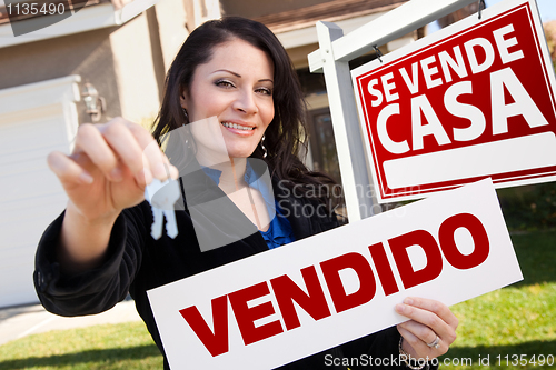 Image of Hispanic Woman Holding Vendido Sign in Front of Se Vende Casa Si