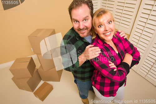 Image of Proud Goofy Couple and Moving Boxes in Empty Room