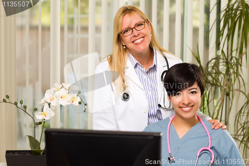 Image of Smiling Mixed Race Female Doctors or Nurses in Office Setting