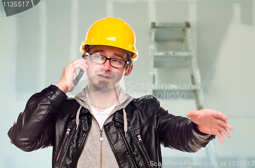 Image of Contractor in Hard Hat on Cell Phone In Unfinished House
