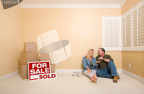 Image of Couple on Floor Near Boxes and Sold Real Estate Signs