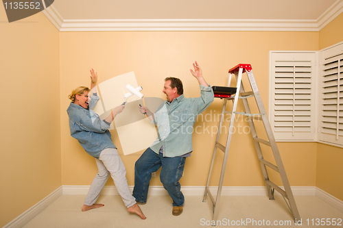 Image of Fun Couple Playing Sword Fight with Paint Rollers