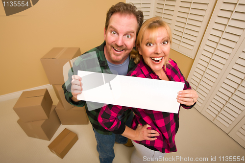 Image of Happy Couple Holding Blank Sign in Room with Packed Boxes