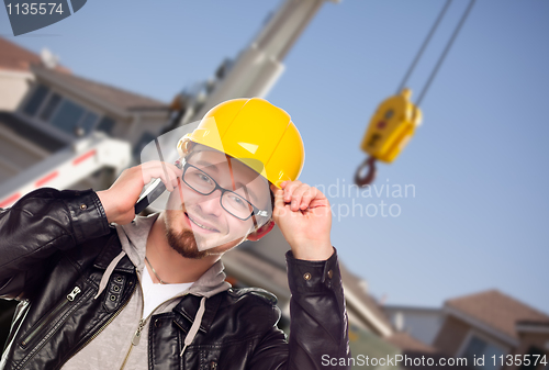 Image of Young Cunstruction Worker on Cell Phone In Front of Crane