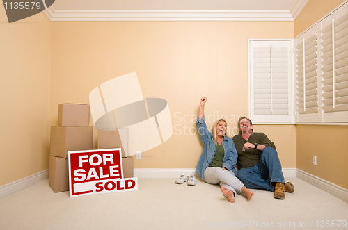 Image of Couple on Floor Near Boxes and Sold Real Estate Signs