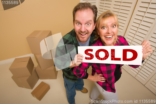 Image of Goofy Couple Holding Sold Sign Surrounded by Boxes