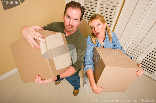 Image of Exhausted Couple Holding Moving Boxes