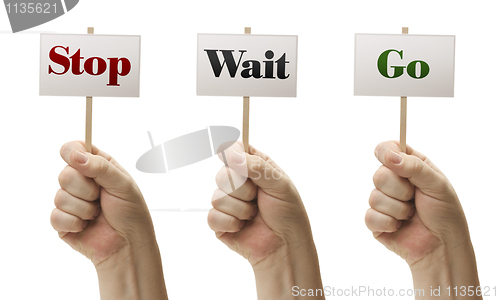 Image of Three Signs In Fists Saying Stop, Wait and Go