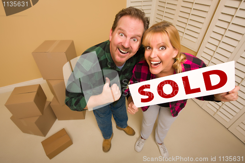 Image of Goofy Couple Holding Sold Sign Surrounded by Boxes