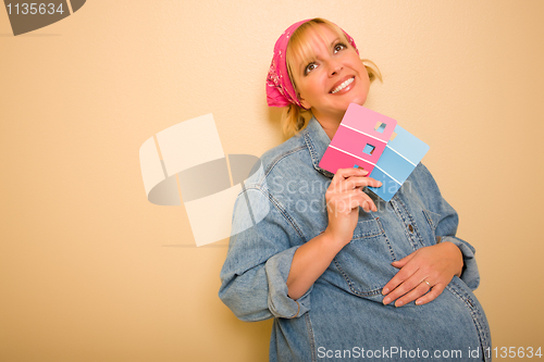 Image of Pensive Pregnant Woman Holding Pink and Blue Paint Swatches

