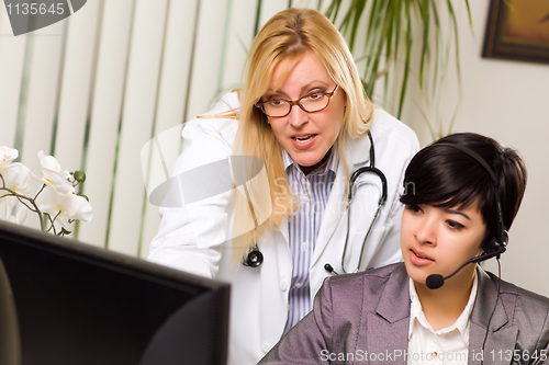 Image of Female Doctor Discusses Work on Computer with Receptionist Assis