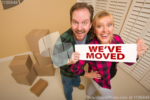 Image of Goofy Couple Holding We've Moved Sign Surrounded by Boxes