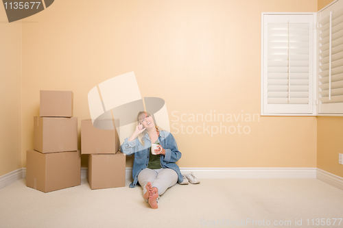 Image of Happy Woman Relaxing Next to Boxes on Floor with Cup