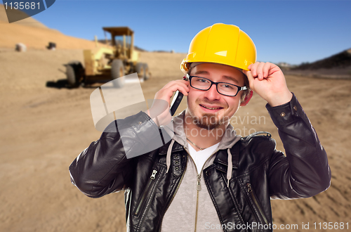 Image of Young Cunstruction Worker on Cell Phone in Dirt Field with Tract