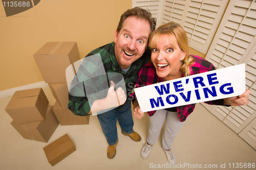 Image of Goofy Couple Holding We're Moving Sign Surrounded by Boxes