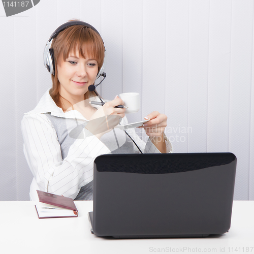 Image of girl-employee hotline is drinking coffee