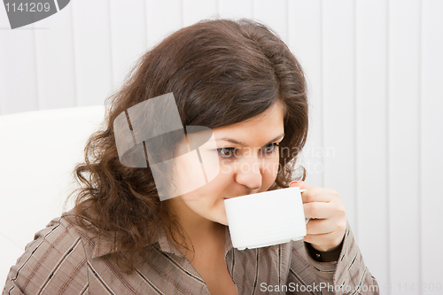 Image of Brunette girl is drinking coffee from a cup