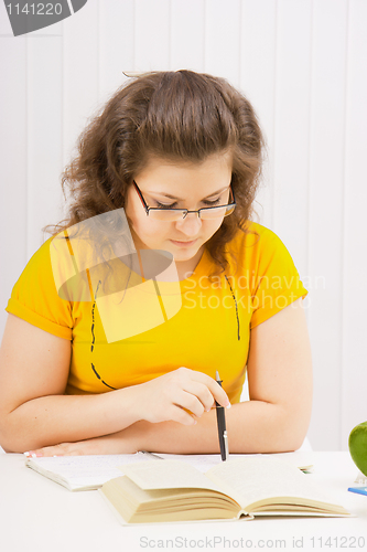 Image of A young woman in spectacles is reading a book