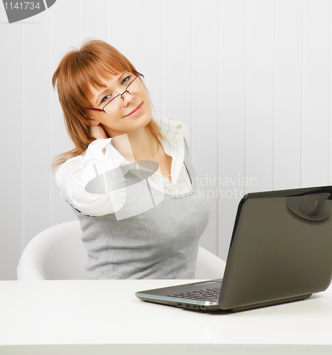 Image of tired girl with a laptop stretches