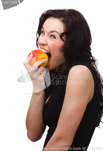 Image of Young attractive woman is biting an apple