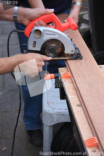 Image of construction worker cutting wood with circular saw