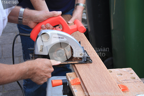 Image of construction worker cutting wood with circular saw