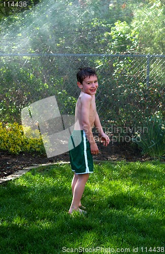 Image of boy sprayed by sprinkler