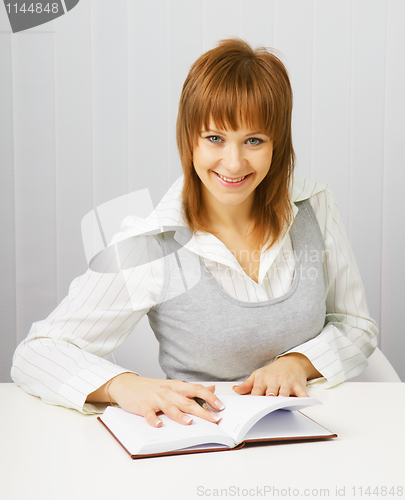 Image of Attractive girl in a white blouse with a notepad and pen