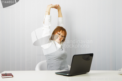 Image of tired girl with a laptop stretches