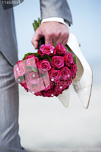 Image of Groom holding flowers en shoes of bride