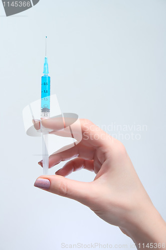 Image of Woman holds in her hand medical suringe with blue solution