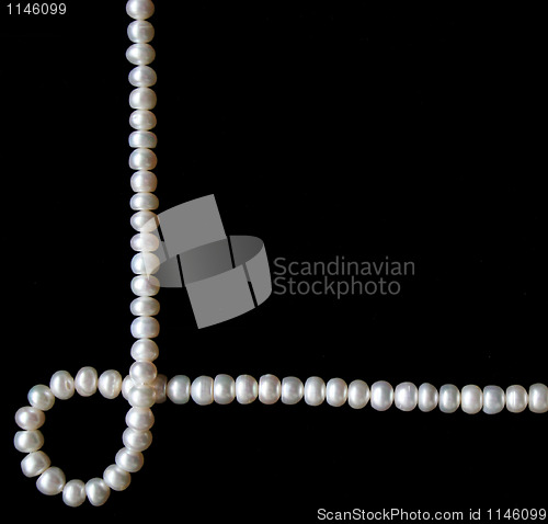 Image of White pearls on the black silk as background