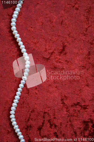 Image of Necklace of white pearls on a terracotta velvet as background 