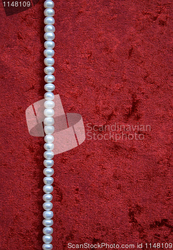 Image of Necklace of white pearls on a terracotta velvet as background 