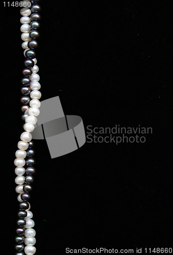 Image of White and black pearls on the black velvet as background