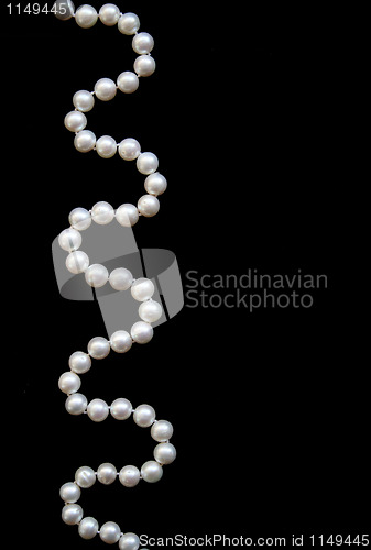 Image of White pearls on the black silk as background 