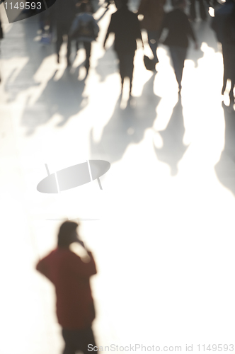 Image of Crowd in sunlight with person on phone