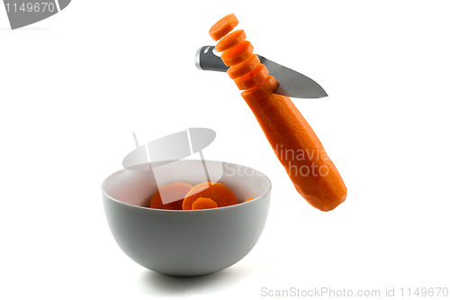 Image of Knife chopping carrot slices into white bowl