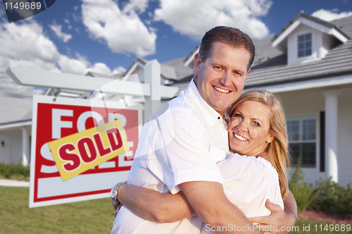 Image of Couple Hugging in Front of Sold Sign and House