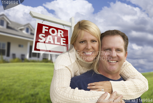Image of Happy Couple Hugging in Front of Real Estate Sign and House