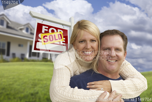 Image of Happy Couple Hugging in Front of Sold Sign and House