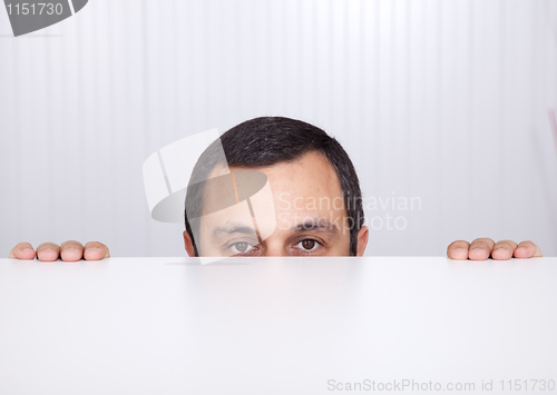 Image of Businessman peeking behind the desk