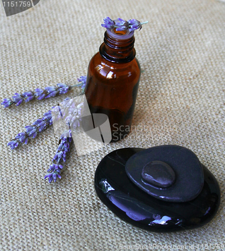 Image of Lavender flowers and bottle of essential oil on sackcloth backgr