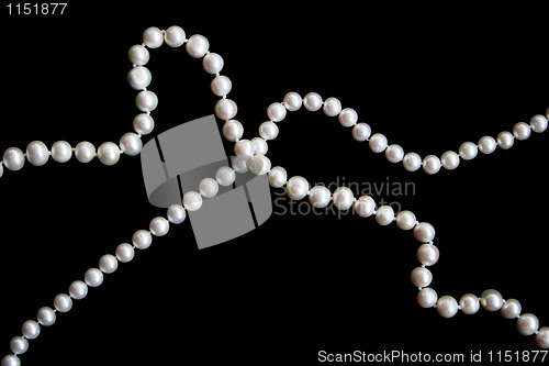 Image of White pearls on the black silk as background 