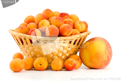 Image of Wicker basket filled with apricots and single peach near